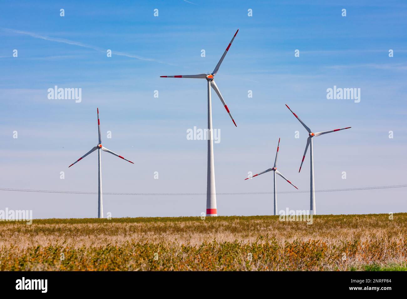 Diverse enormi turbine eoliche per la produzione di energia elettrica con campi in primo piano Foto Stock