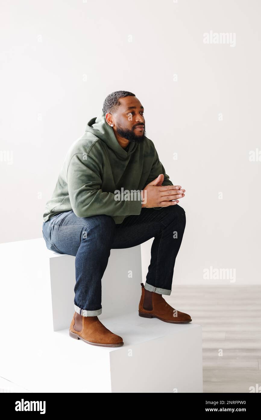 uomo nero maturo ed elegante seduto sui gradini al coperto Foto Stock