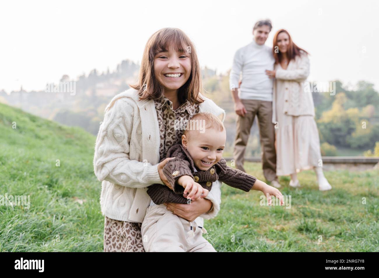 Una ragazza adolescente caucasica abbraccia il suo fratellino all'aperto Foto Stock