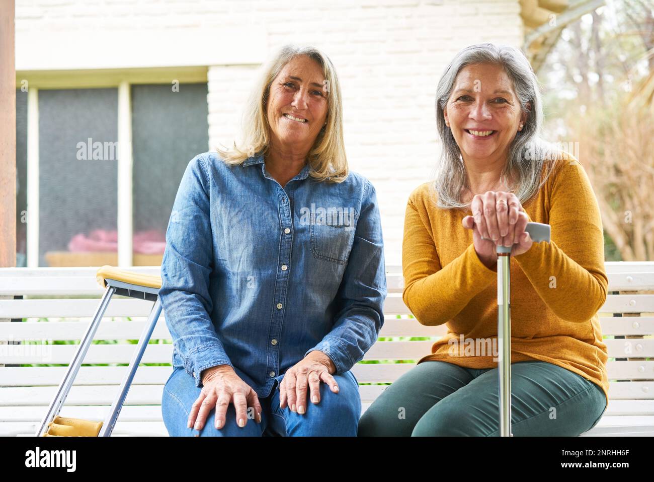 Ritratto di felice donna anziana seduta con un'amica su panchina in giardino Foto Stock