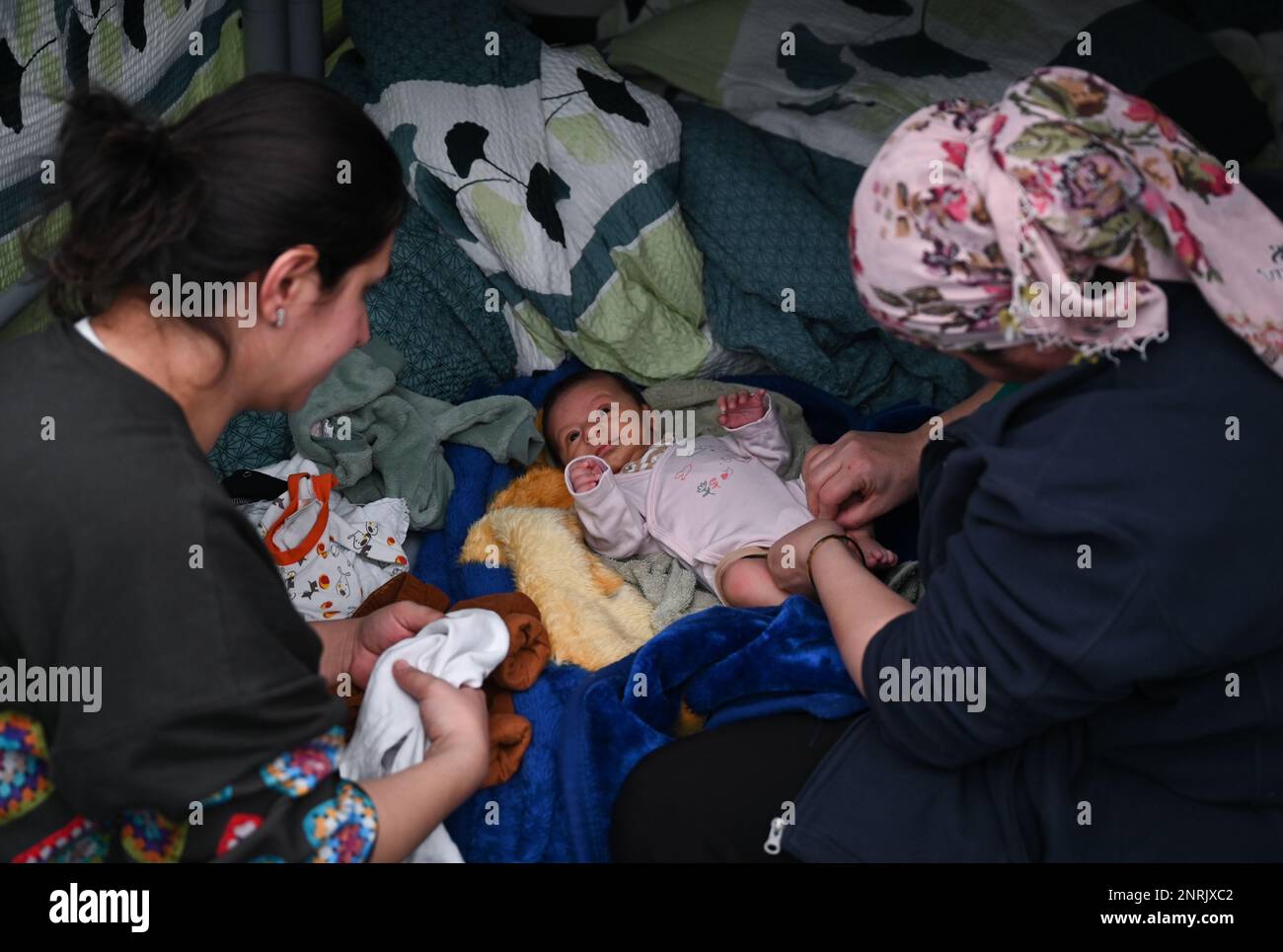 PRODUZIONE - 10 febbraio 2023, Assia, Bensheim: Due donne fuggite dalla Turchia si prendono cura di un bambino di 1 mesi (la madre è a sinistra) in una delle tende del rifugio profughi. Le città e le comunità difficilmente possono accogliere il numero di rifugiati. Il distretto di Bergstrasse non è l'unico a chiedere un maggiore sostegno da parte dei governi federali e statali. Foto: Arne Dedert/dpa Foto Stock
