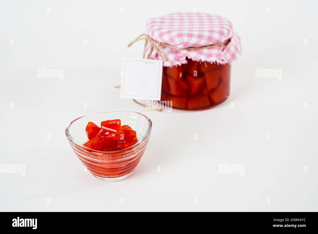 Vasetto tradizionale di marmellata di mele cotogne con etichetta vuota e piccola tazza isolata su sfondo bianco. Foto Stock