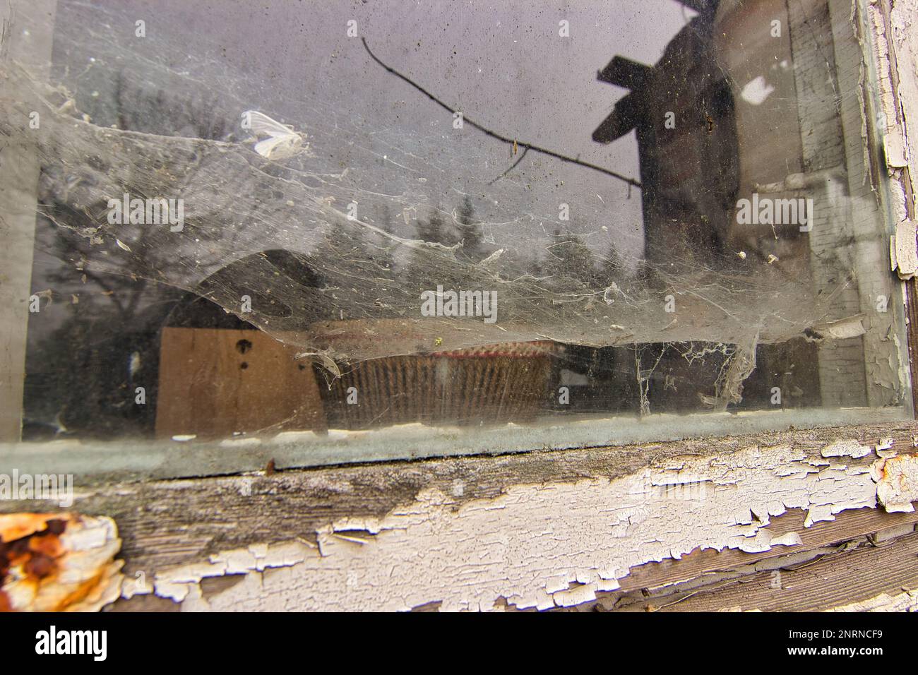 Luogo di residenza abbandonato: Finestra di vetro coperta da spessi ciottoli, incorniciata da un telaio decaduto, finestra di legno. Foto Stock