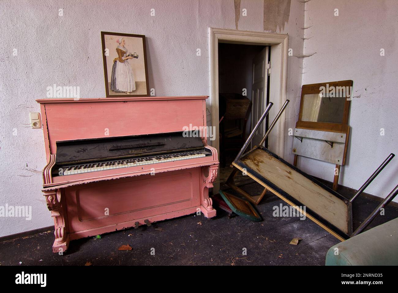 Casa residenziale luogo abbandonato: Stanza luminosa con un vecchio pianoforte rosa pallido sul quale si trova un'antica immagine di una cameriera. Foto Stock