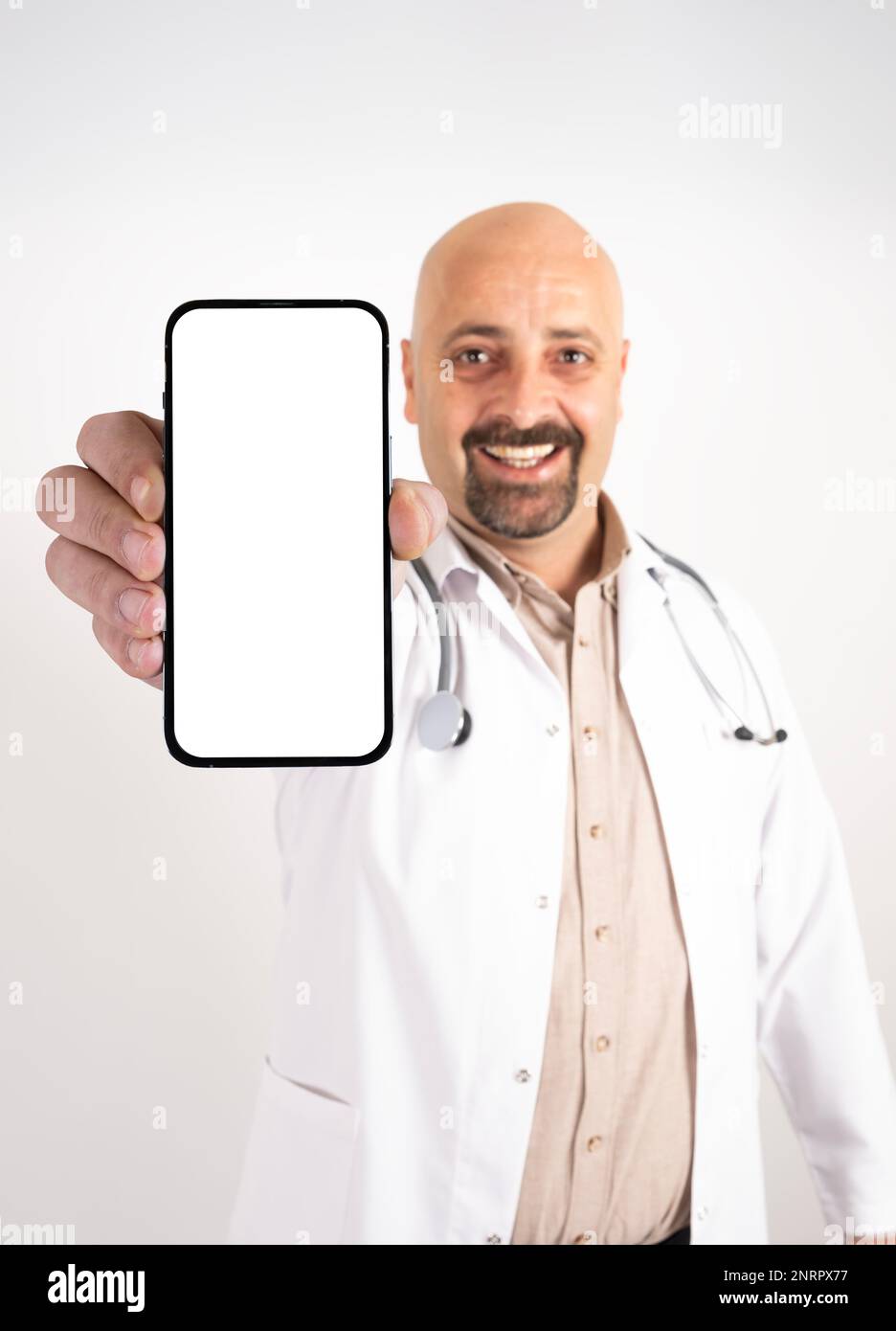 Ritratto di medico allegro che mostra lo schermo vuoto di smartphone per la simulazione. Operaio professionista dell'ospedale millenario caucasico che indossa uniforme bianca. Foto Stock