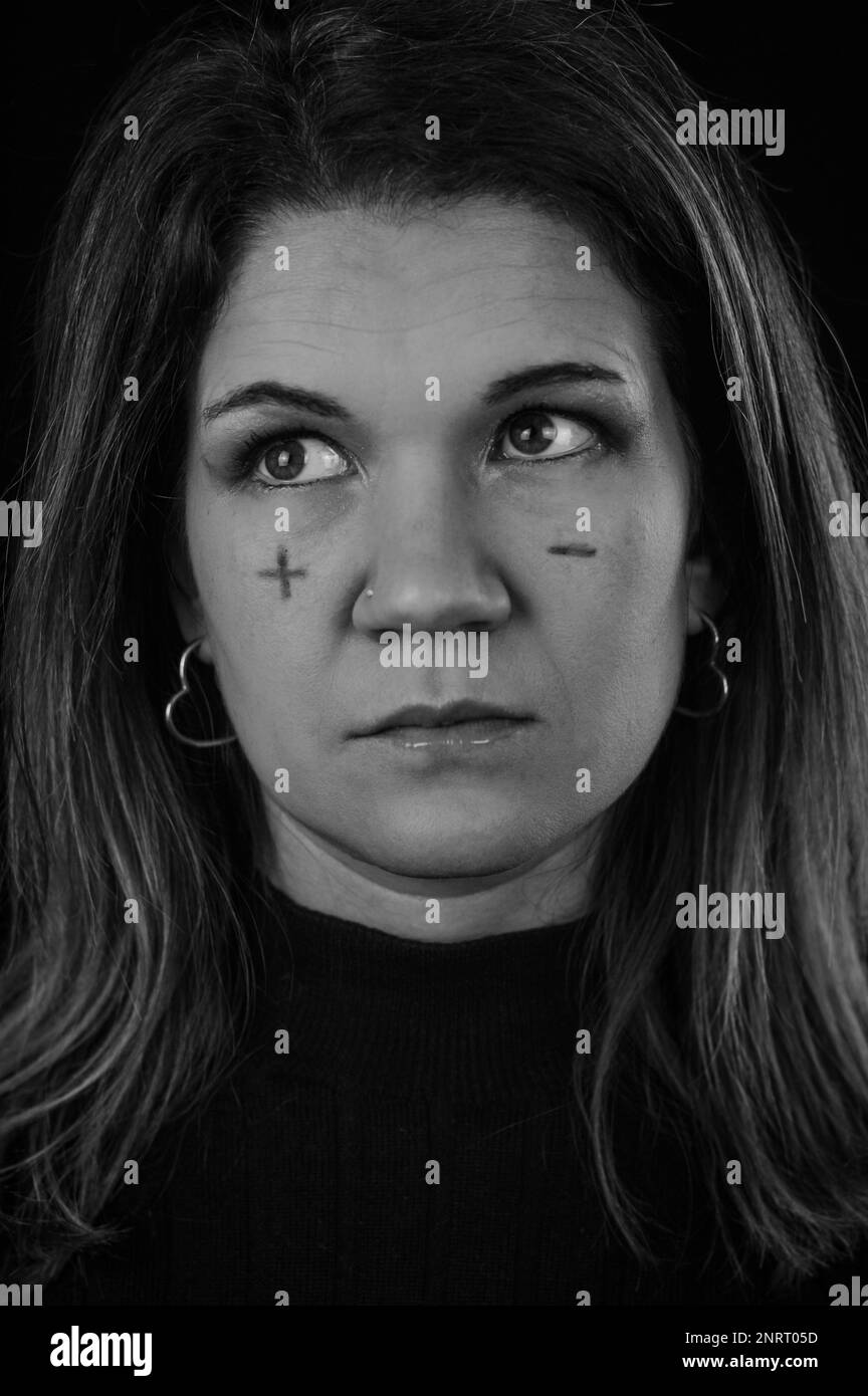 prendere decisioni - ritratto di una bella donna bionda con segni più e meno scritti sulle guance e guardando in dubbio Foto Stock