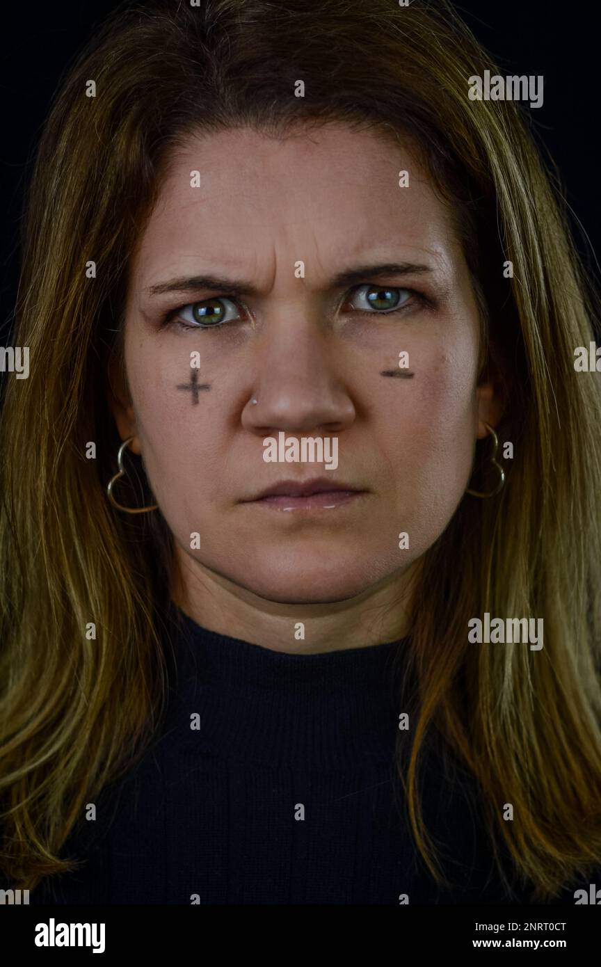 prendere decisioni - ritratto di una bella donna bionda con segni più e meno scritti sulle guance e accigliati in confusione Foto Stock