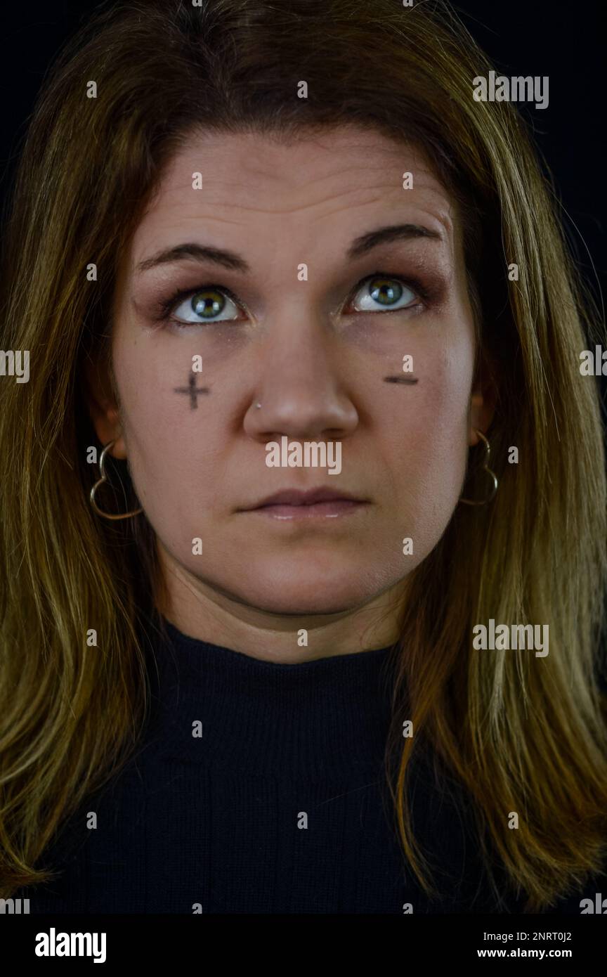 prendere decisioni - ritratto di una bella donna bionda con segni più e meno scritti sulle guance e guardando in dubbio Foto Stock