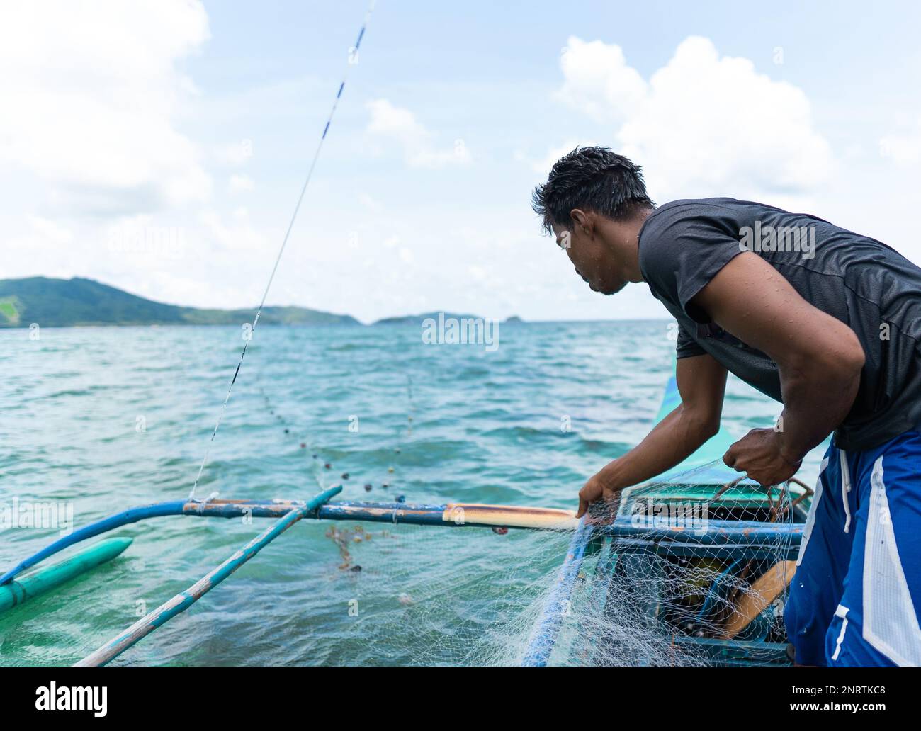 giovane pescatore che raccoglie la sua rete di pesca, isole filippine. spazio di copia Foto Stock