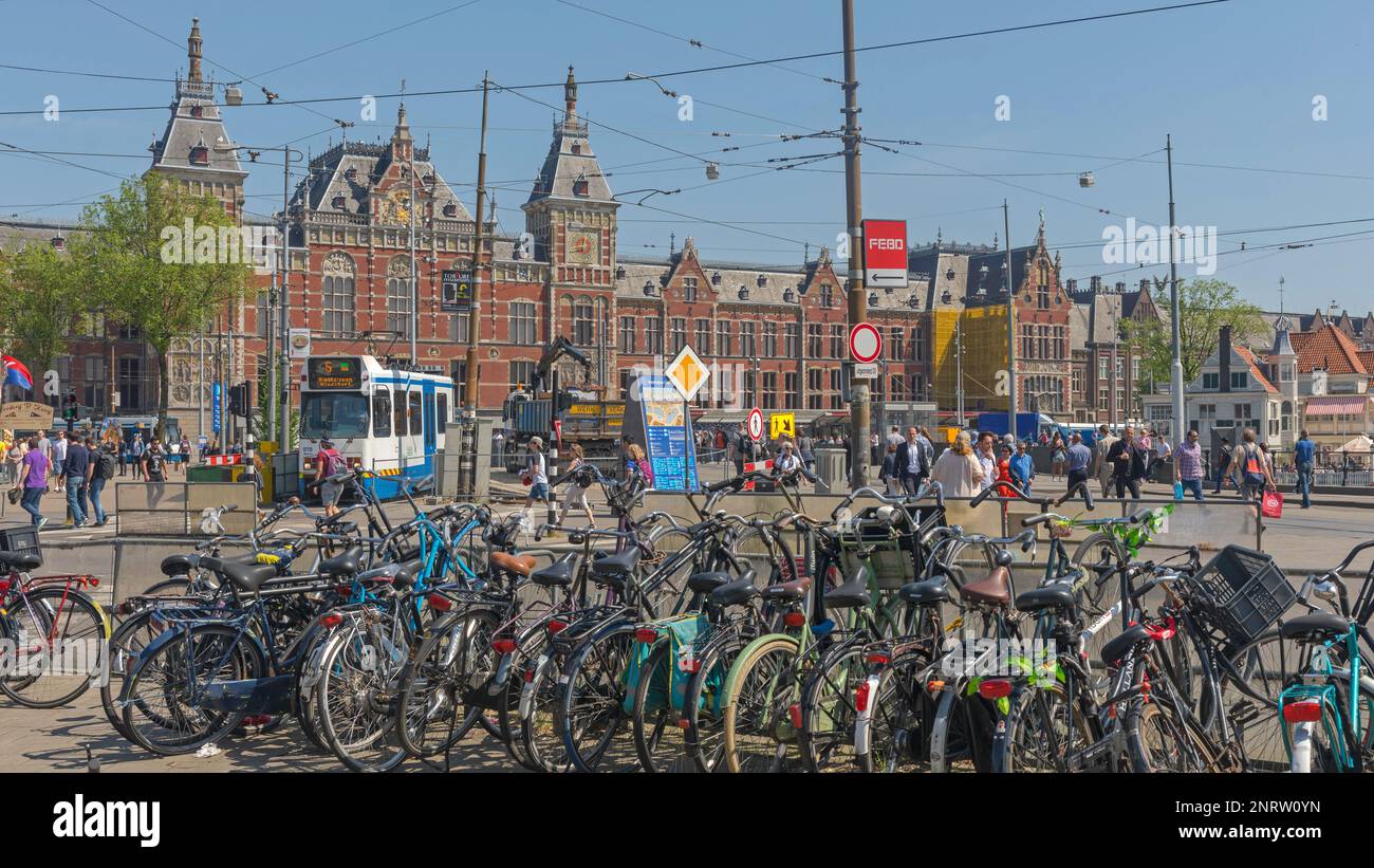 Amsterdam, Paesi Bassi - 14 maggio 2018: Biciclette Parcheggio mezzi pubblici Tram e Stazione Centrale edificio. Foto Stock
