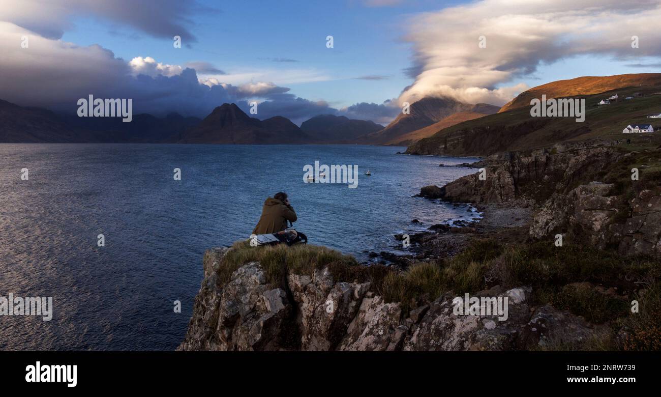 Un fotografo scatta foto guardando verso nord ovest attraverso Loch Scavaig verso la catena montuosa di Cuillin nel villaggio di Elgol sull'isola di Skye. Foto Stock