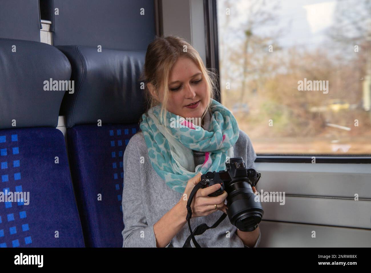 Giovane donna su un treno che tiene una mano di macchina fotografica professionale (immagine simbolo) Foto Stock