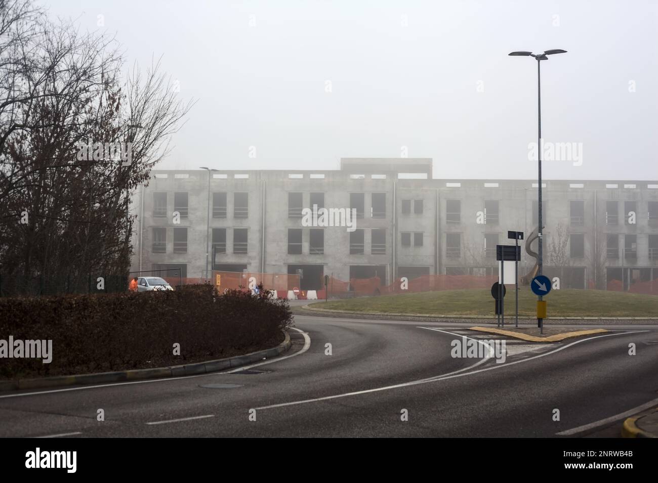 Edificio abbandonato ai margini di una rotonda in una giornata di nebbia nella campagna italiana Foto Stock