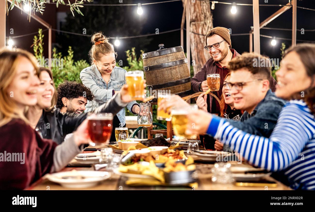 Giovani uomini e donne che si divertono a bere fuori al patio birreria all'aperto - incontro sociale e bevande concetto di stile di vita sulla gente felice godendo fine settimana Foto Stock
