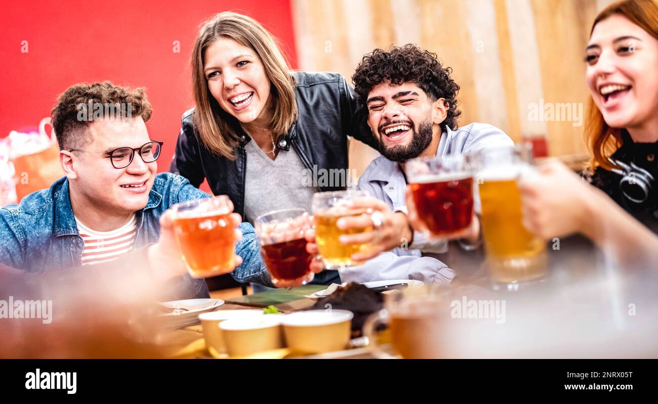 Giovani amici alla moda che brindano birra mangiando cibo misto in un ambiente fresco al coperto - concetto di vita di incontro sociale sulla gente felice godendo del tempo di ritrovo Foto Stock