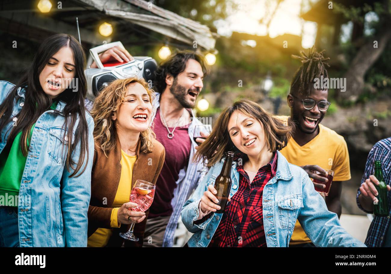 Gruppo di amici multiculturali che si diverte a fare il tifo con bevande e bottiglie di birra - gente milleniale che si diverte a festa in villa privata insieme - Yo Foto Stock