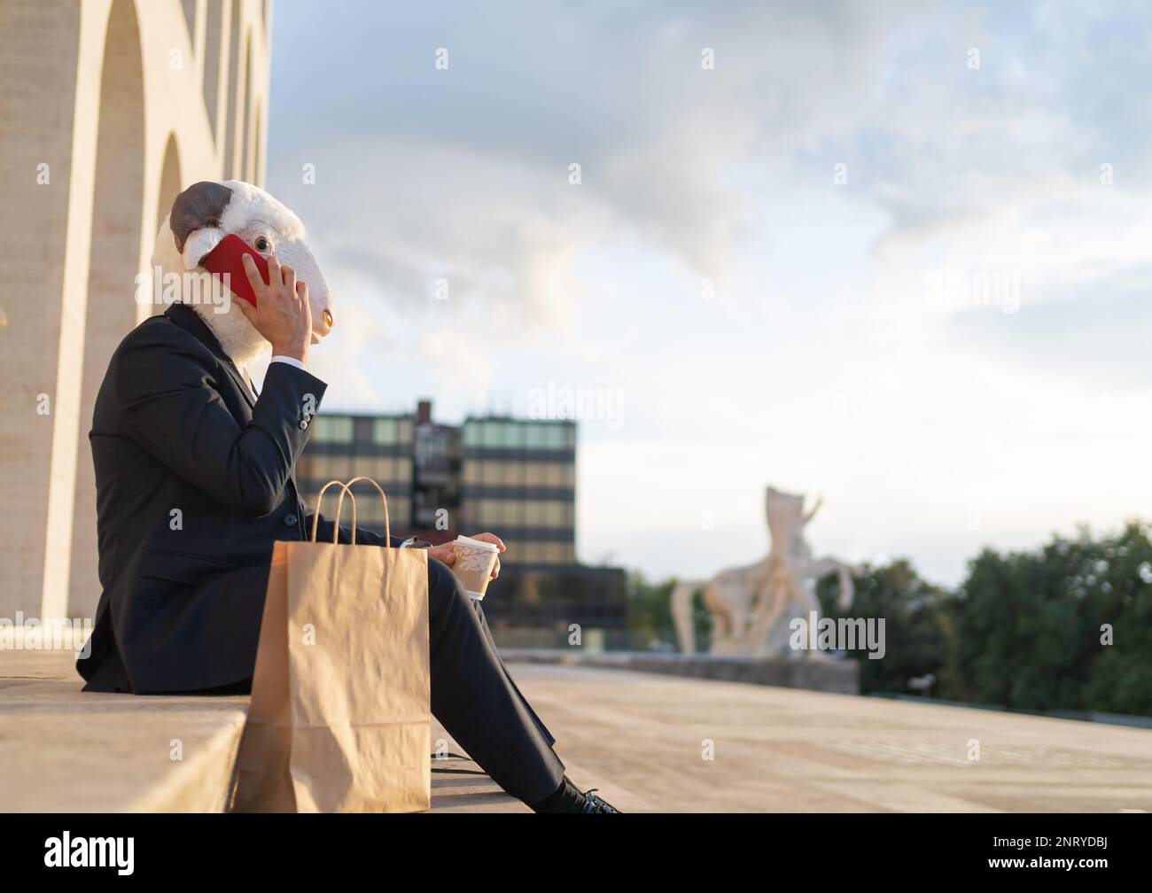vista laterale del business con la testa di pecora seduta a parlare al telefono nel suo pranzo pausa, spazio copia, fotografia concettuale Foto Stock