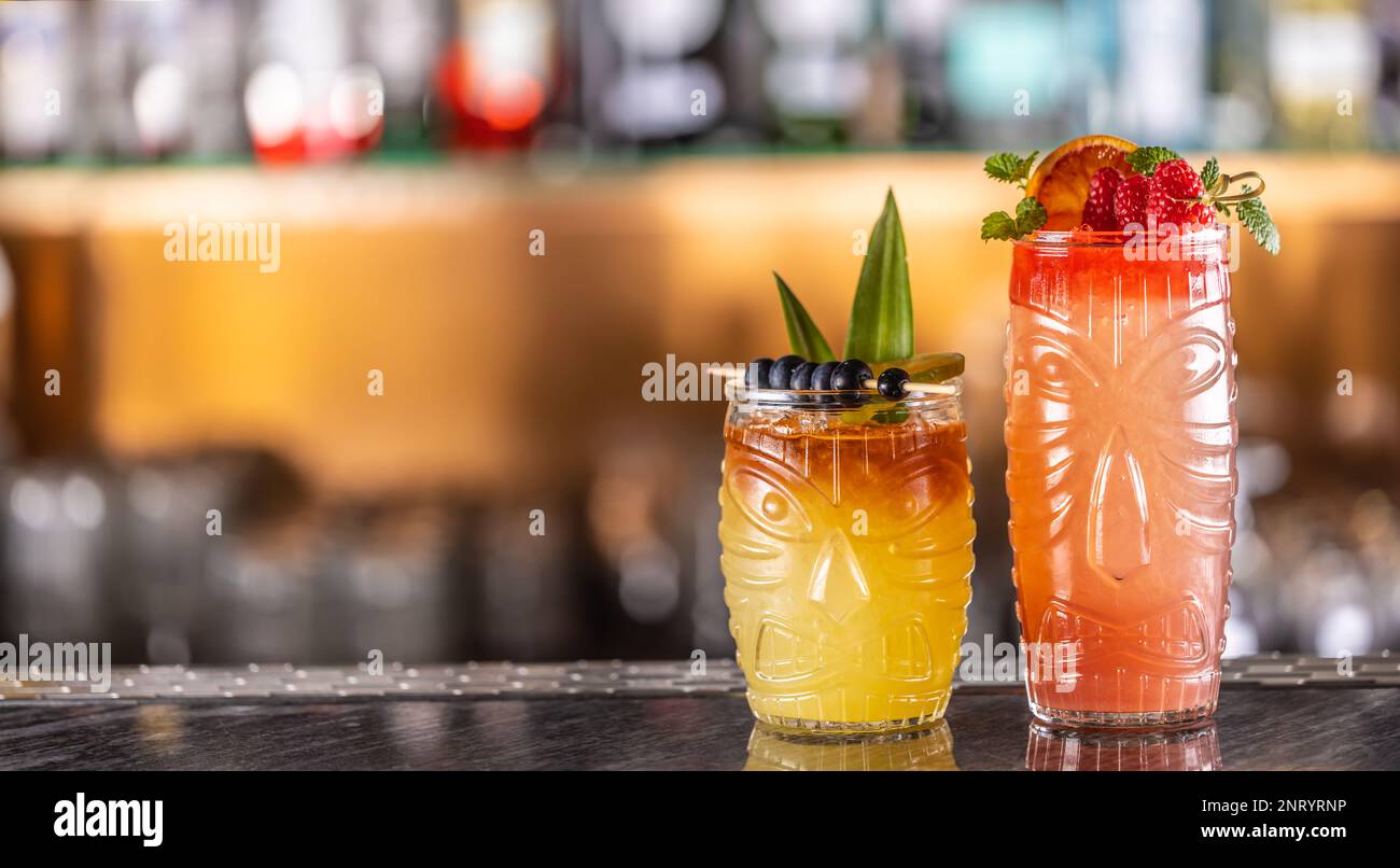 Mai Tai cocktail in bicchieri hawaiani guarniti con ananas, mirtilli e fragole al banco bar. Foto Stock