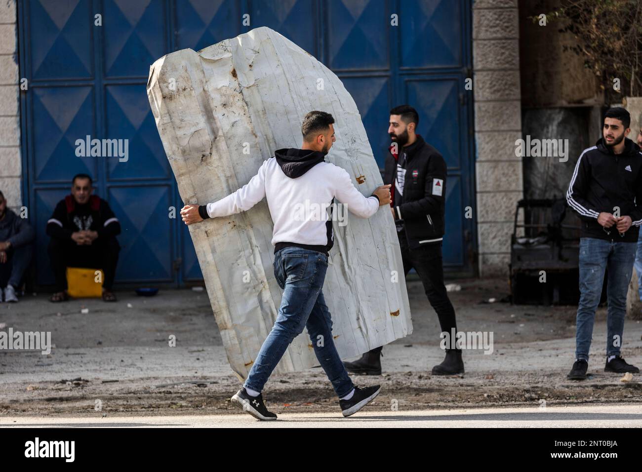 Huwara. 27th Feb, 2023. Un uomo palestinese porta parte della distruzione della struttura dopo che i coloni hanno messo le case e le automobili sul fuoco dopo la morte di due israeliani quando il loro veicolo è stato sparato su ad un incrocio a sud della città palestinese di Nablus. Credit: Ilia Yefimovich/dpa/Alamy Live News Foto Stock