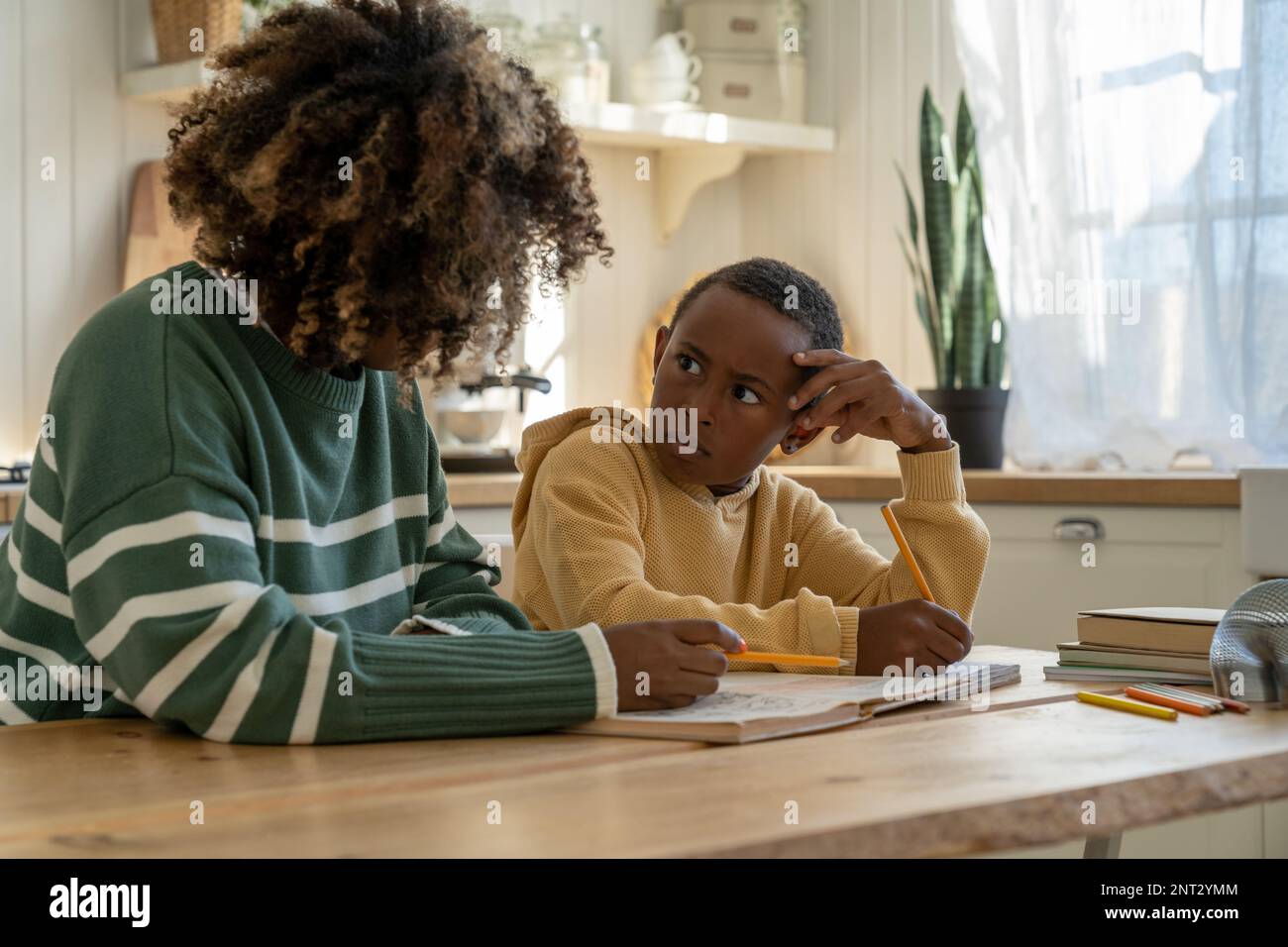 Sorpreso dispiaciuto bambino misto razza ragazzo guardando tutor dando lezioni private a casa Foto Stock
