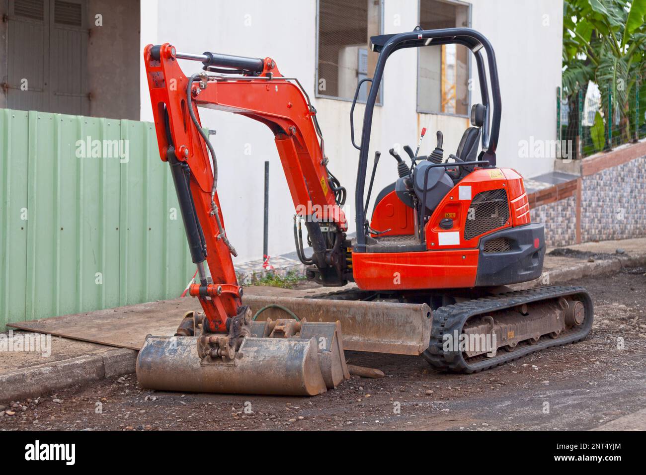 Mini escavatore rosso su una strada laterale. Foto Stock