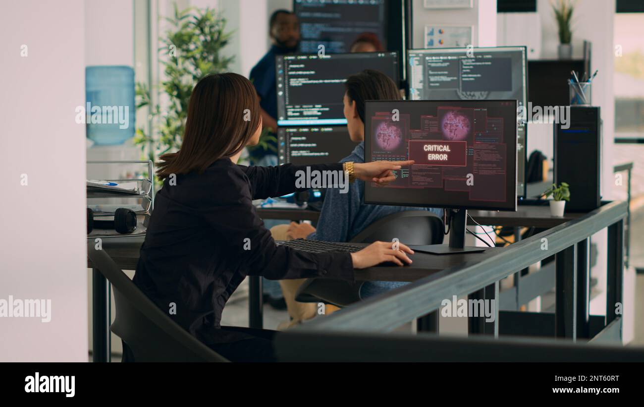 Diversi team di codificatori che hanno il server hacked e crash di sistema, in esecuzione messaggio di errore critico lampeggiante sullo schermo con più monitor. Visualizzazione di avvisi di hacking, cyber crimine. Foto Stock