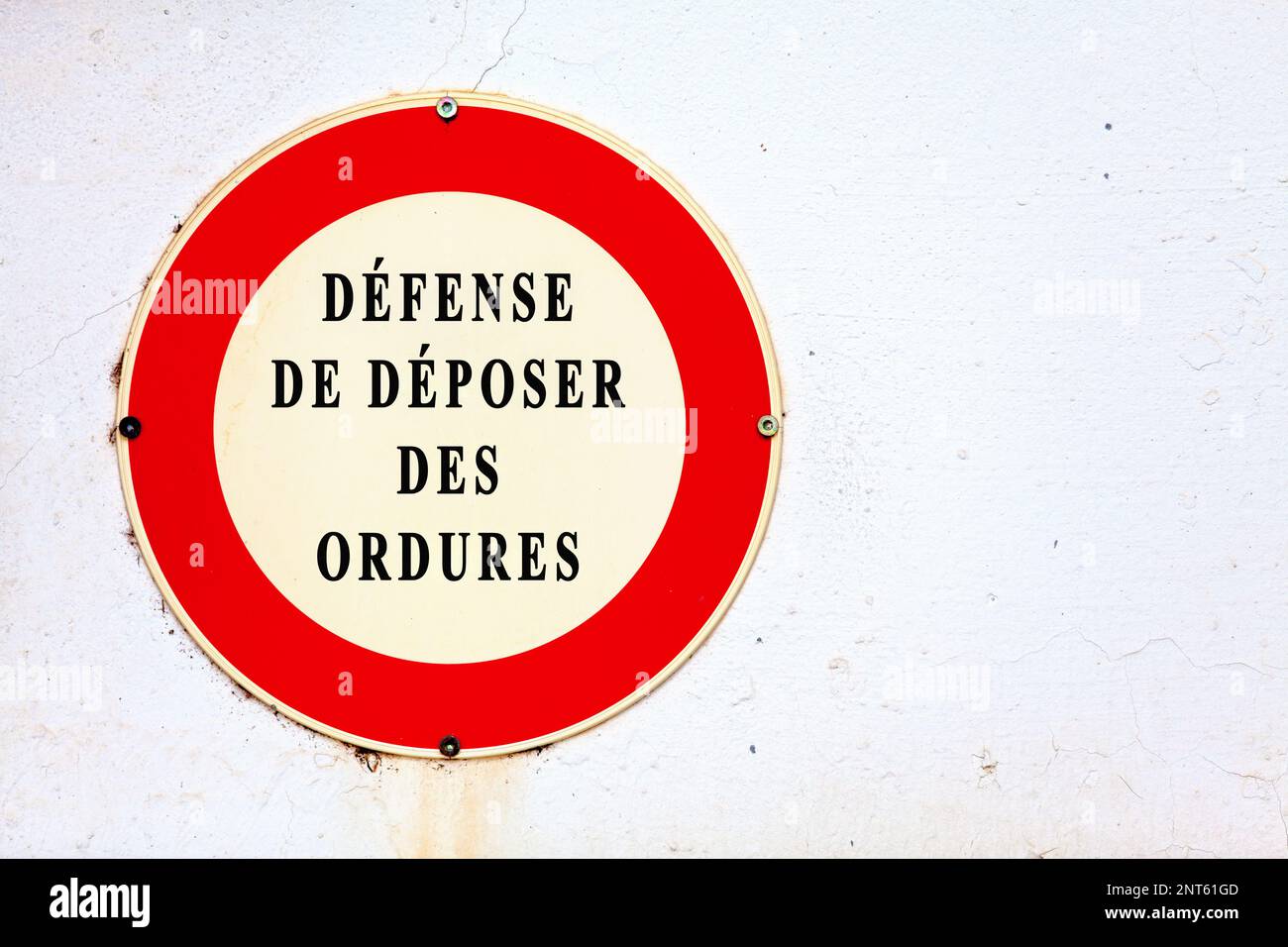 Cartello avvitato su una parete dipinta di bianco che recita in francese 'Défense de déposer des ordures', che significa in inglese 'proibito depositare rifiuti'. Foto Stock