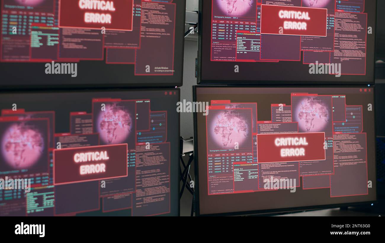 Scrivania vuota con più monitor che mostrano un avviso di arresto anomalo del sistema e un messaggio di errore critico lampeggiante sullo schermo. Computer che visualizza un avviso di violazione della sicurezza e un avviso di pirateria informatica, malfunzionamento del computer. Foto Stock