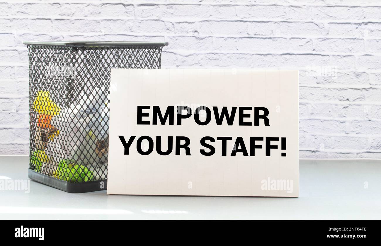 Affari e finanza. Sul tavolo sono presenti due matite, un cactus, una calcolatrice e un blocco note con IL TESTO EMPOWER YOUR STAFF. Foto Stock