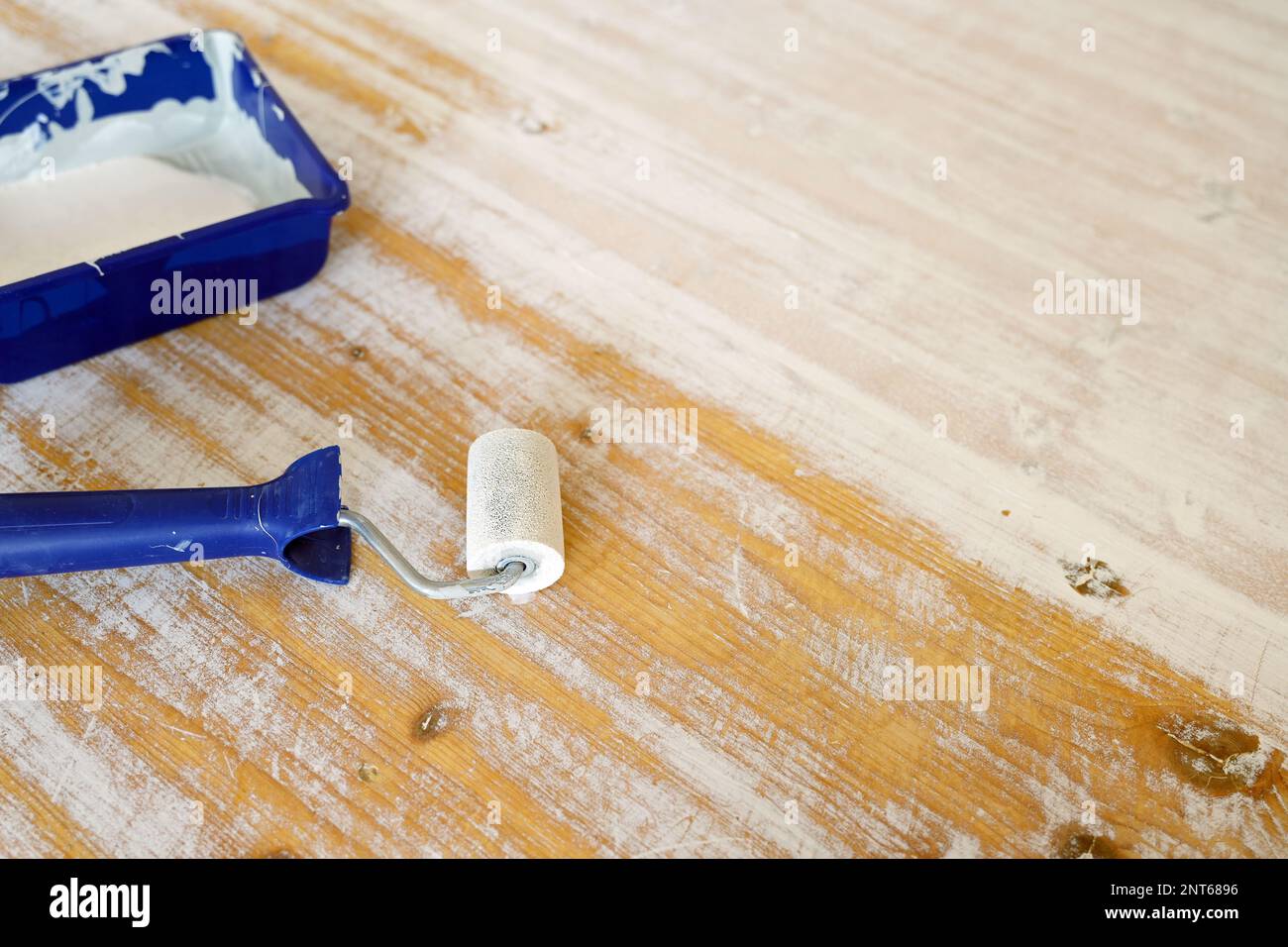 Lacca bianca in un vassoio di vernice blu e rullo per rinnovare il rivestimento su un vecchio tavolo, ristrutturazione di mobili e concetto artigianale, spazio copia, focus selezionato Foto Stock