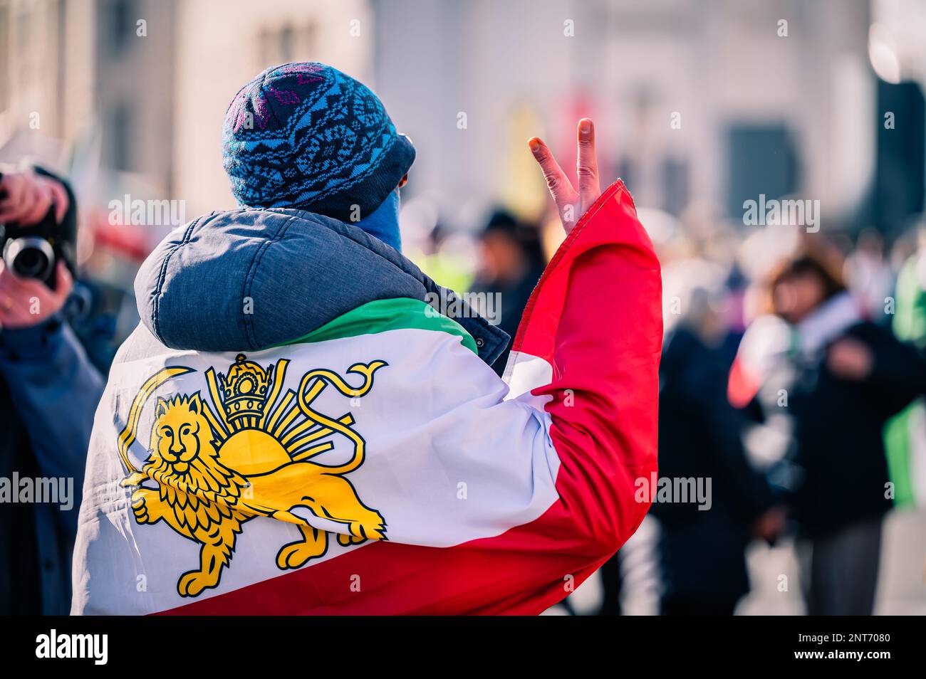 Uomo che indossa la bandiera pro-monarchia a sostegno del cambio di regime in Iran. Foto Stock