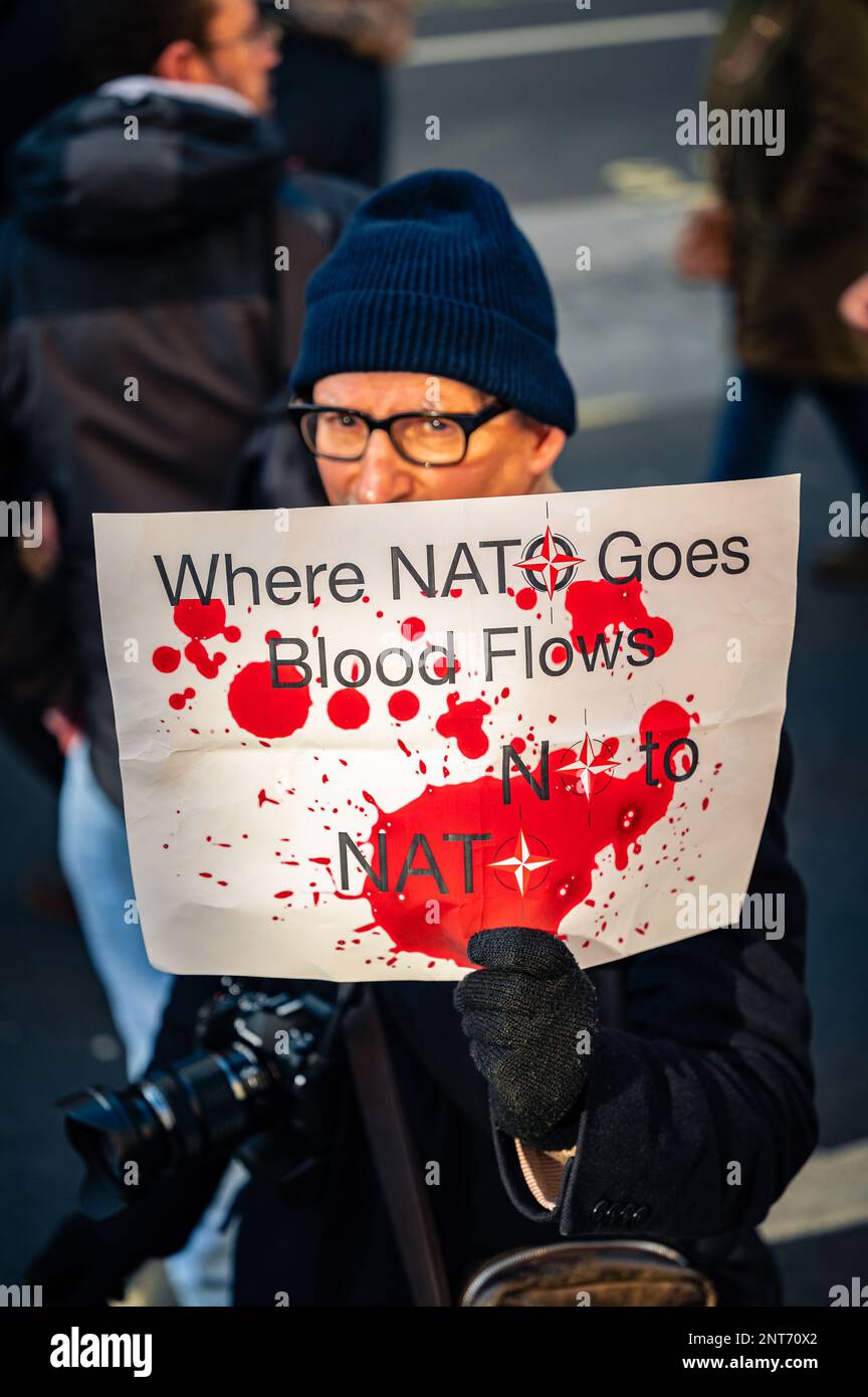 Misterioso uomo che tiene un cartello 'No 2 NATO' alla marcia Stop the War a Trafalgar Square, Londra (febbraio 2023). Foto Stock