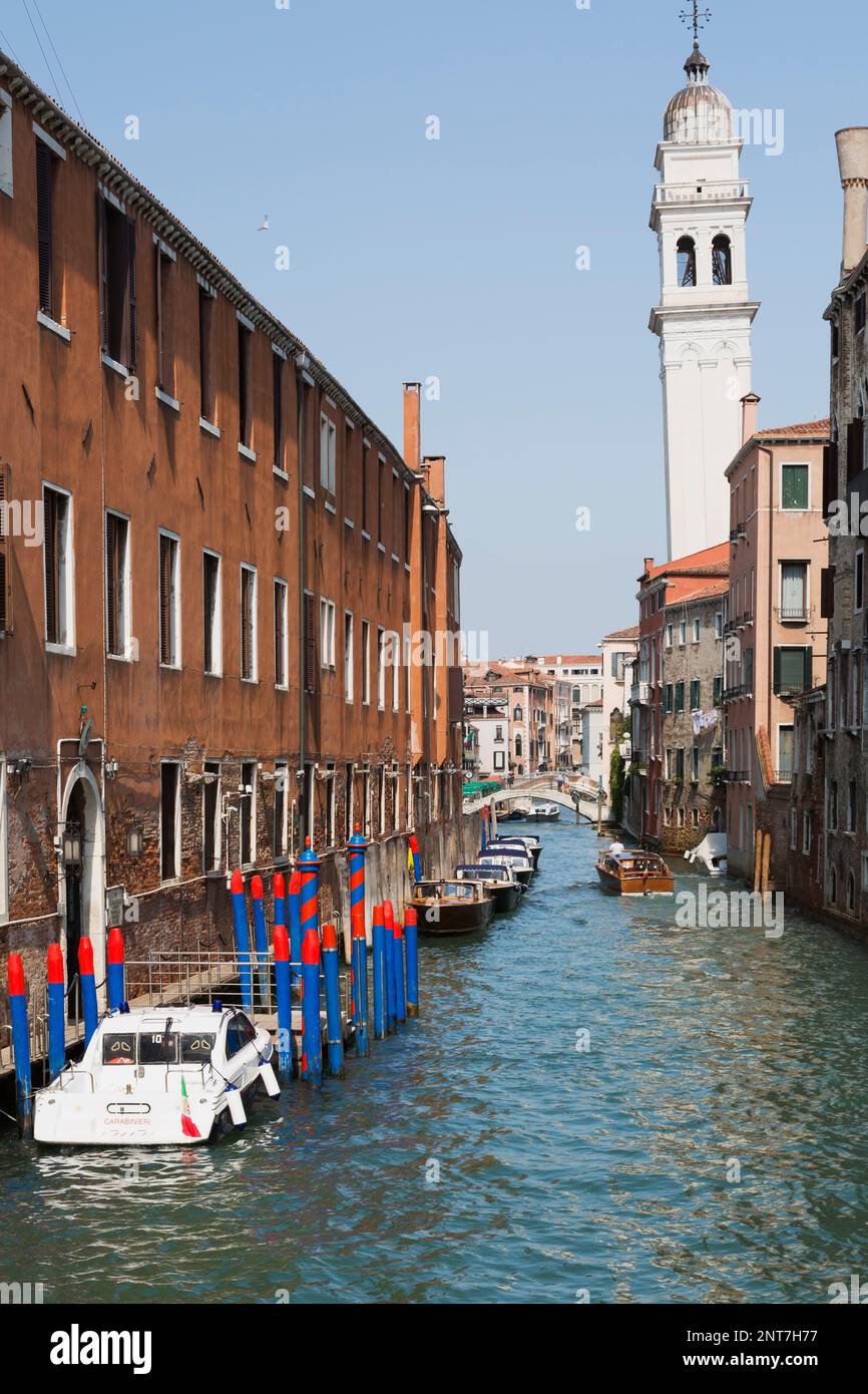 Barche ormeggiate e taxi d'acqua sul canale stretto e vecchi edifici residenziali, chiesa pendente campanile, San Marco, Venezia, Italia. Foto Stock