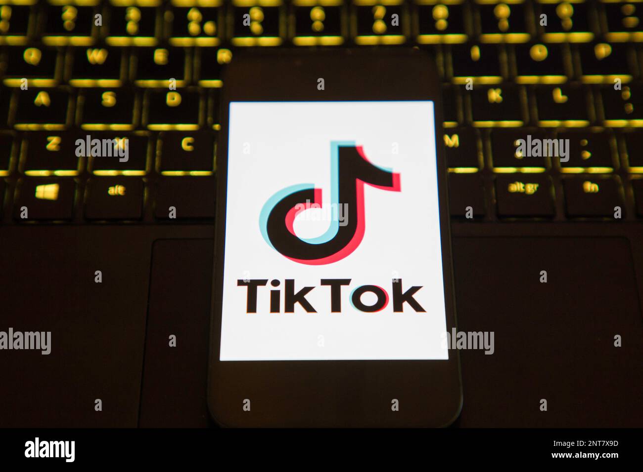 Schermata di caricamento dell'app Tik Tok su un telefono cellulare seduto su un computer portatile illuminato Foto Stock