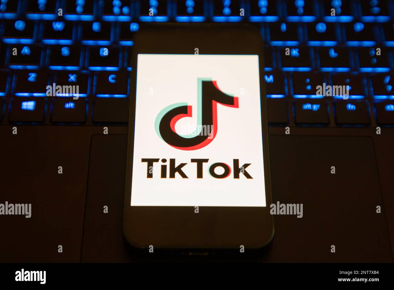 Schermata di caricamento dell'app Tik Tok su un telefono cellulare seduto su un computer portatile illuminato Foto Stock