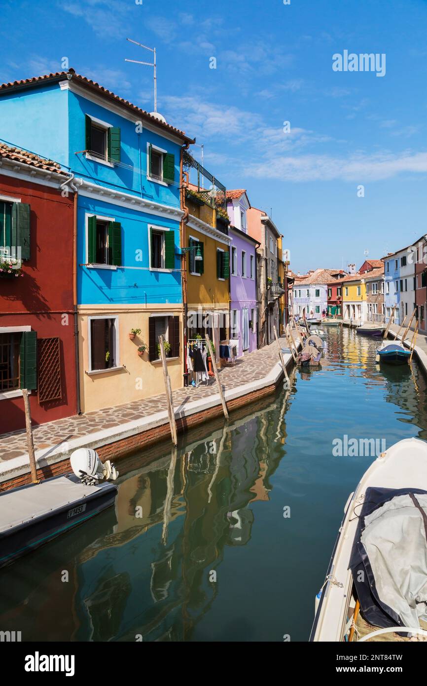 Barche ormeggiate sul canale fiancheggiato da case colorate e negozi, Isola di Burano, Laguna di Venezia, Venezia, Veneto, Italia. Foto Stock