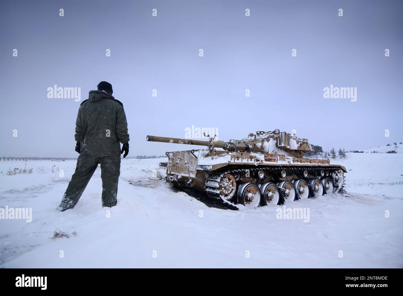 Un membro dell'equipaggio di un carro armato e di un carro armato in una giornata fredda e innevata al confine siriano Foto Stock