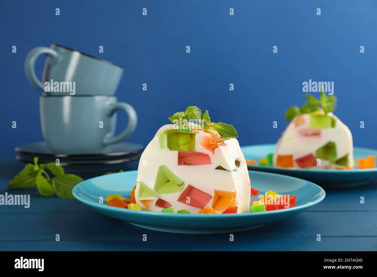 Delizioso dessert di gelatina di vetro spezzato su un tavolo di legno blu Foto Stock