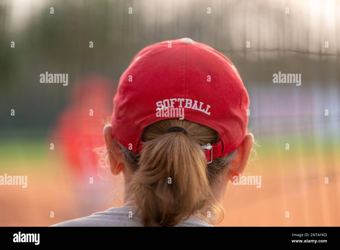 Vista dal retro di una donna, ragazza, capelli castani, in un cappellino da baseball con la parola softball sul retro. Foto Stock