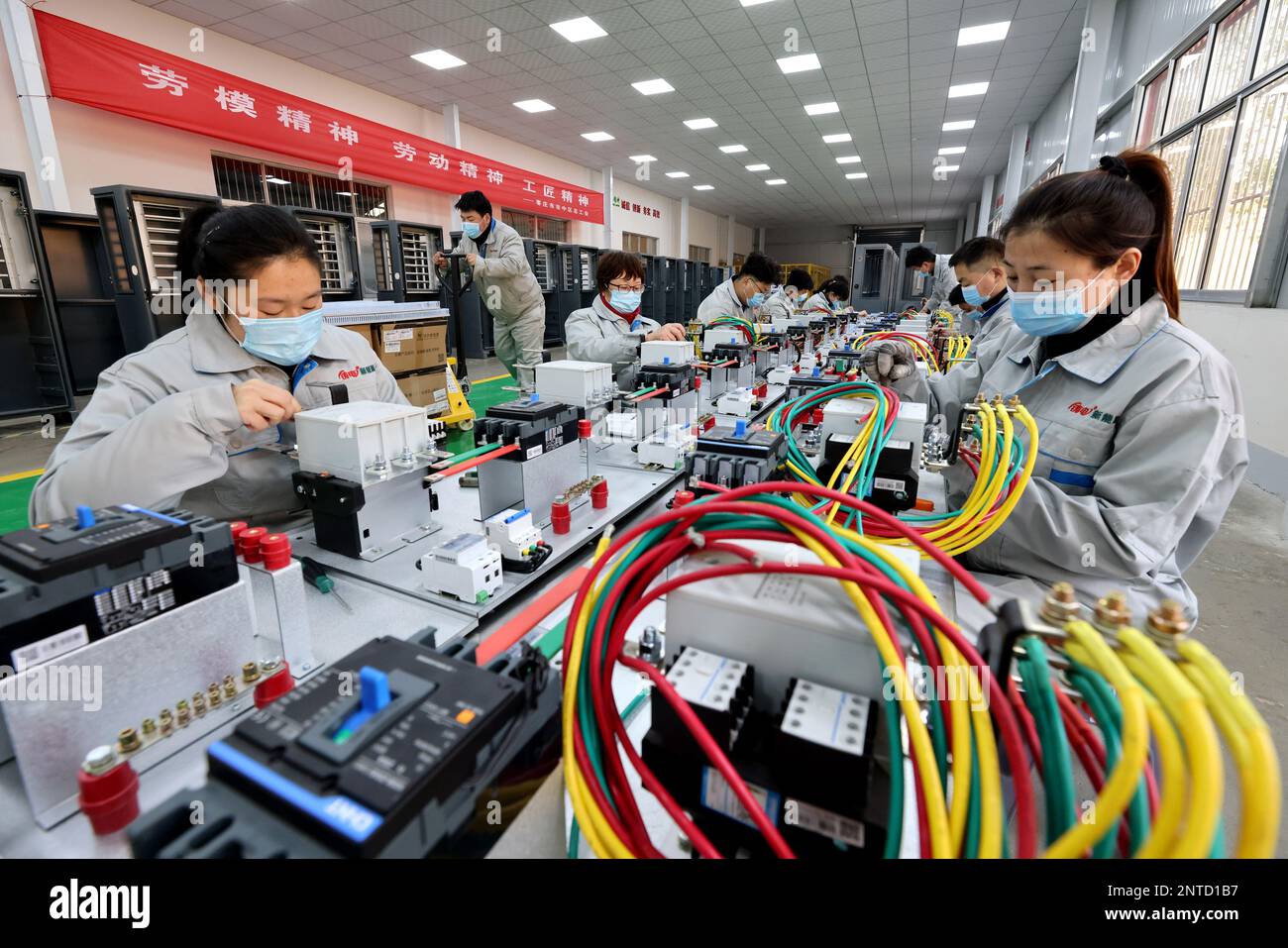 ZAOZHUANG, CINA - 27 FEBBRAIO 2023 - lavoratori qualificati fanno attrezzature di ricarica per veicoli di nuova energia in un'officina di Shandong Dingsheng Electric EQ Foto Stock