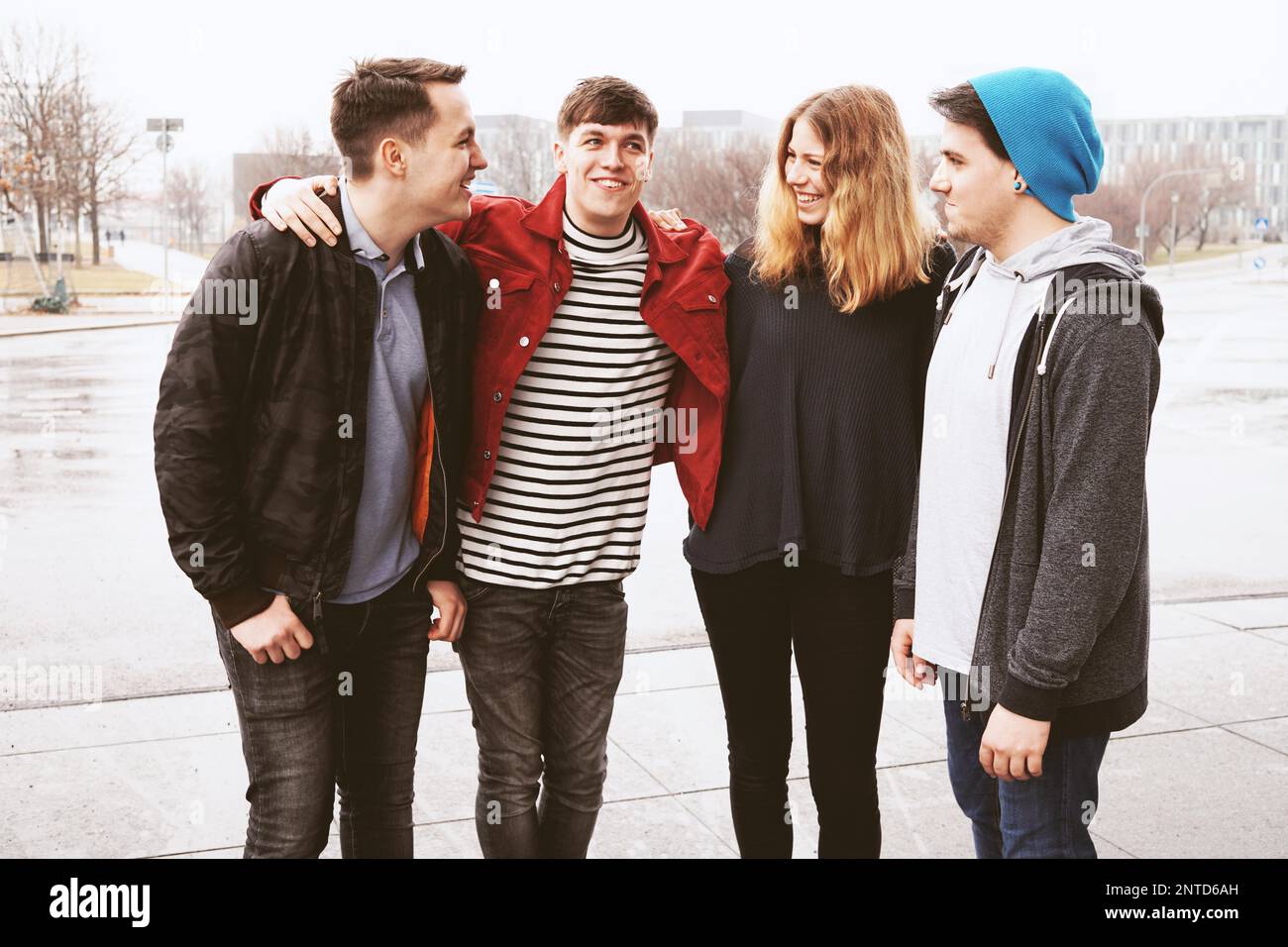 Il gruppo di quattro giovani adolescenti urbano amici divertendosi e ridere insieme nonostante il maltempo - candida persone reali Foto Stock