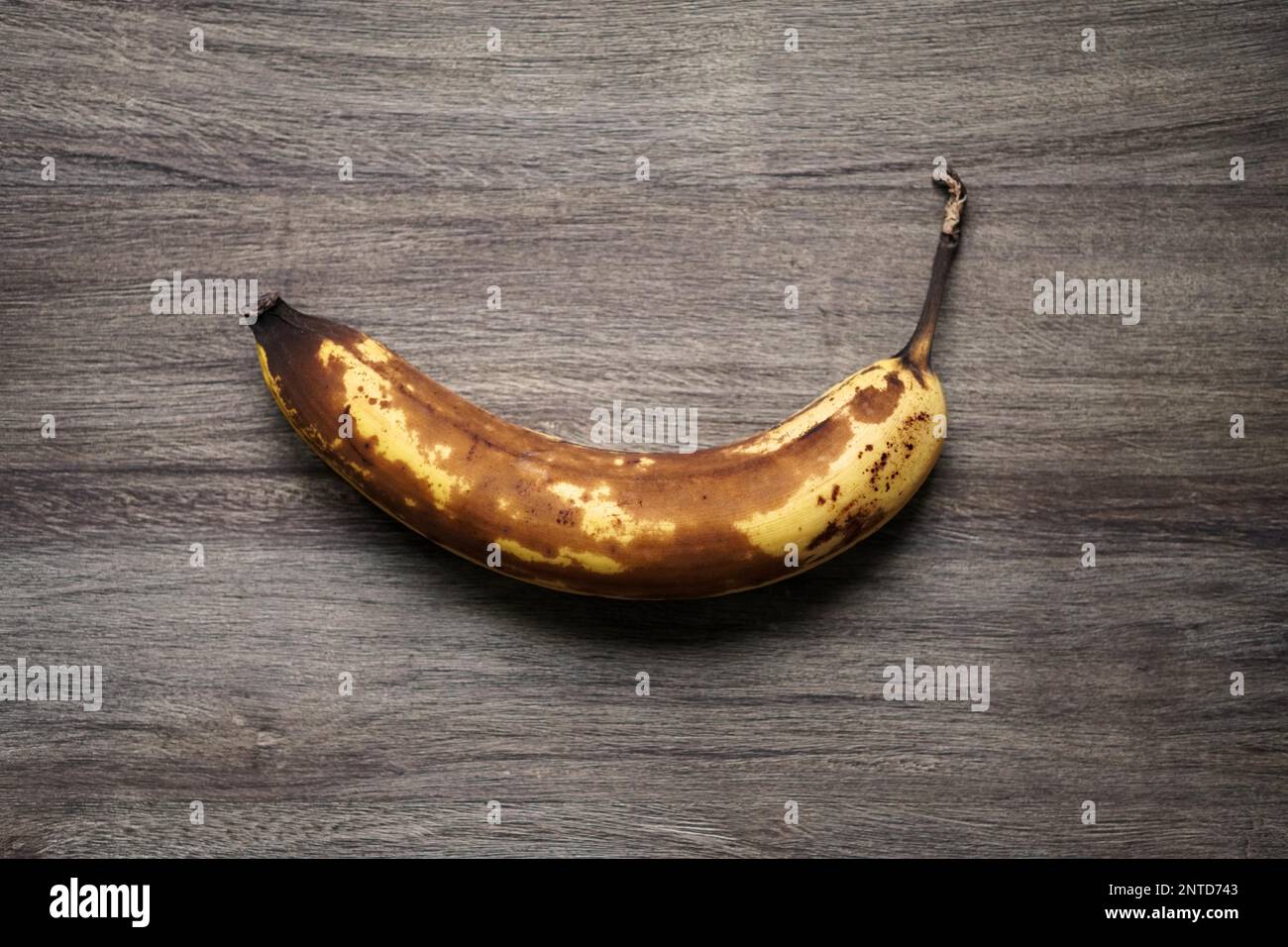 vista dall'alto di frutta a banana overrmature con pelle marrone su sfondo rustico in legno Foto Stock