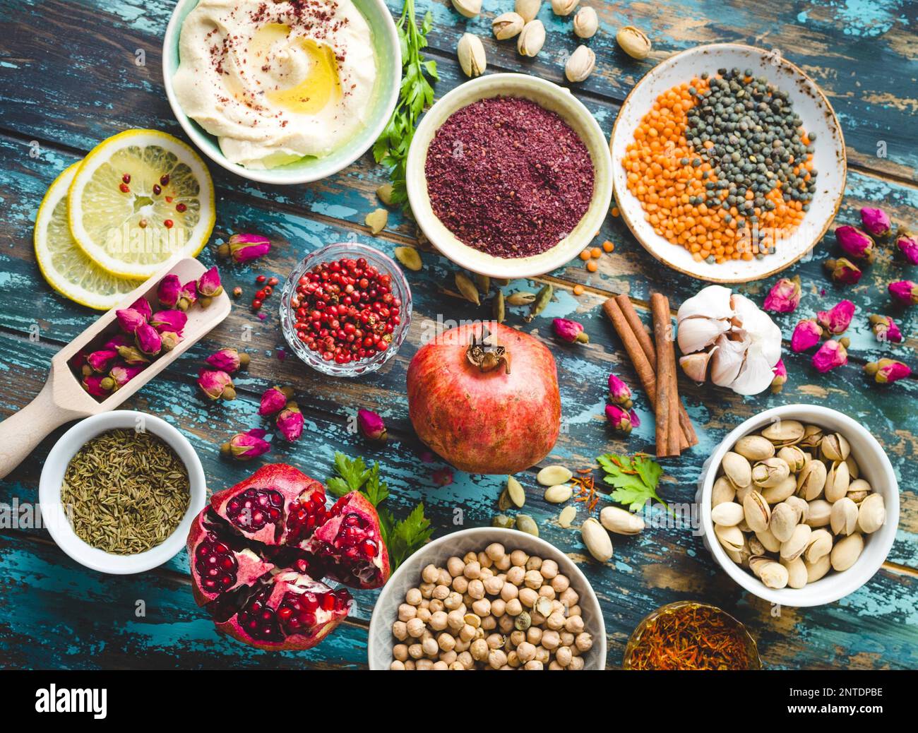 Ingredienti arabi per il cibo mediorientale. Ingredienti della cucina araba su sfondo di legno blu. Hummus, ceci, lenticchie, boccioli di rosa, spezie Foto Stock
