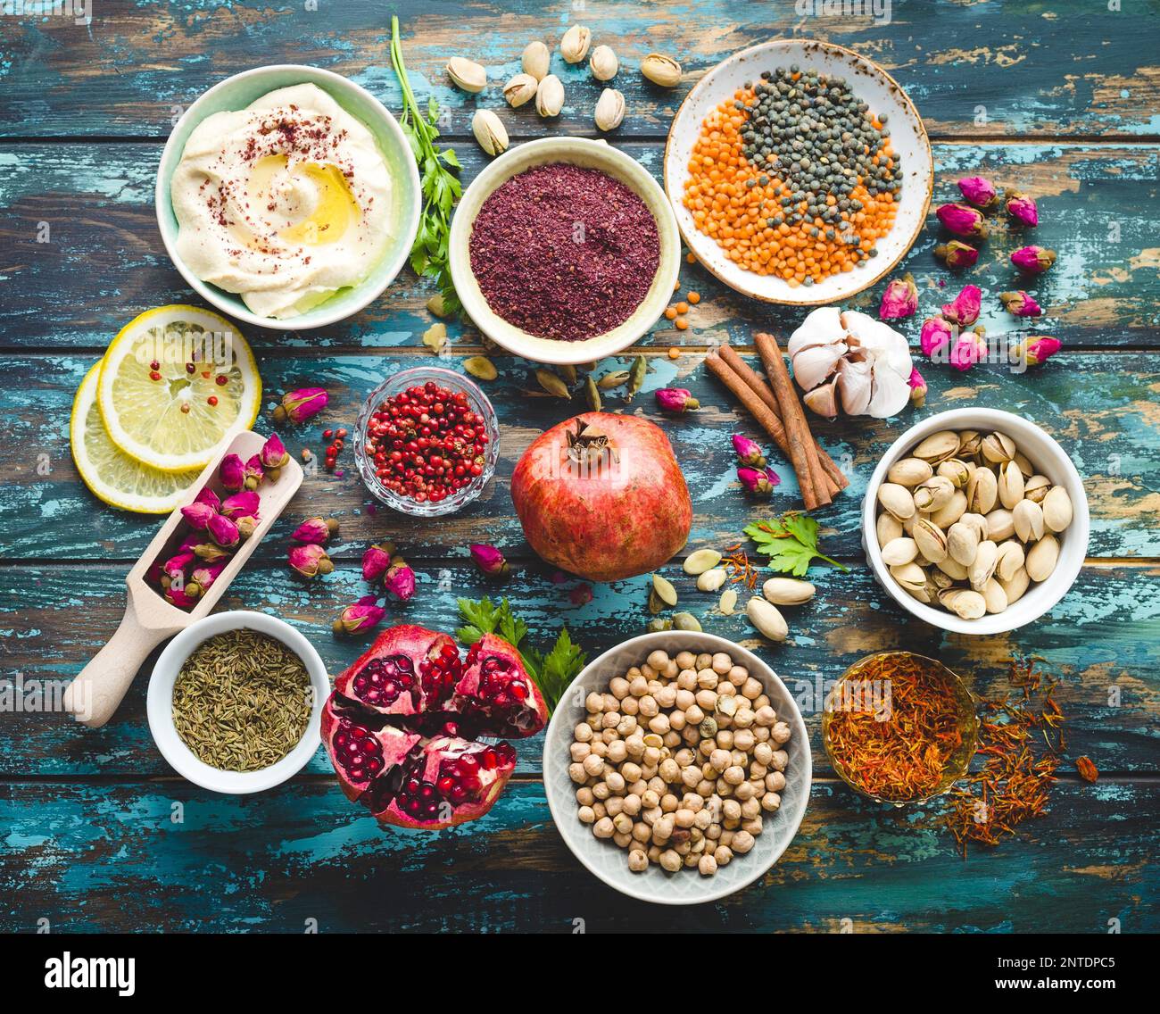 Ingredienti arabi per il cibo mediorientale. Ingredienti della cucina araba su sfondo di legno blu. Hummus, ceci, lenticchie, boccioli di rosa, spezie Foto Stock