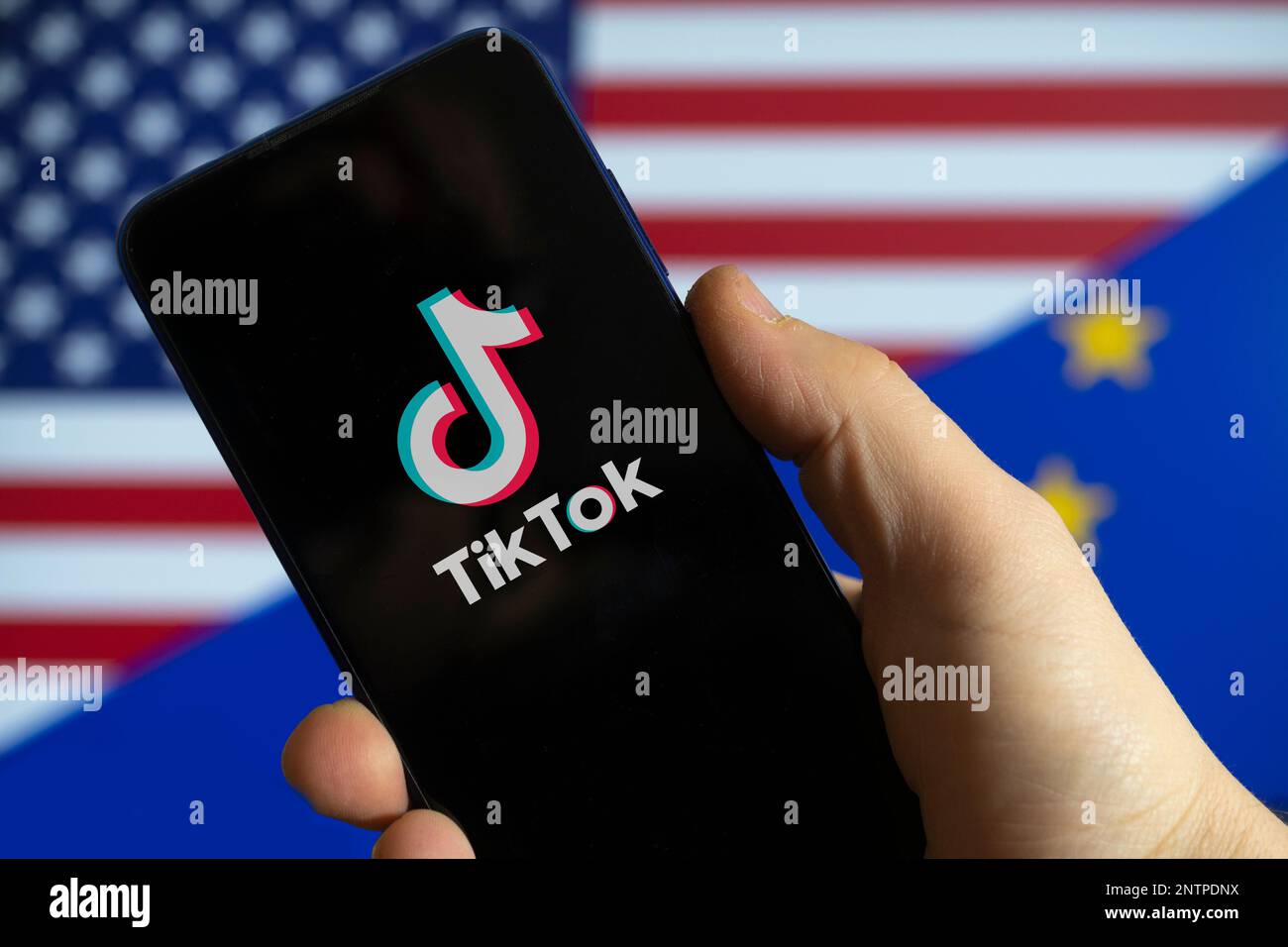 Carrara, Italia - 28 febbraio 2023 - il logo TikTok con le bandiere USA ed UE sullo sfondo Foto Stock