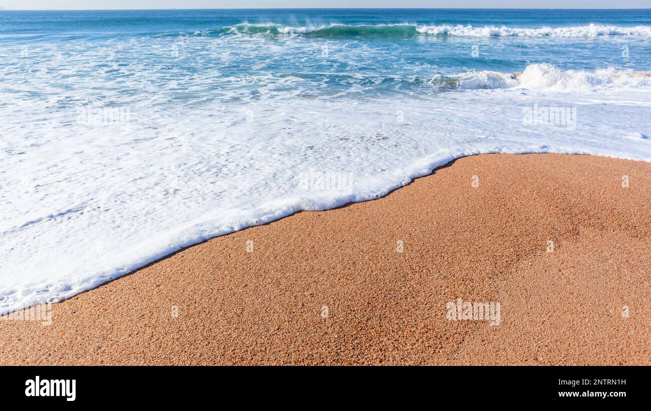 Spiaggia blu oceano onde cielo closeup acqua bianca schiuma onda lavaggio lungo la sabbia costa. Foto Stock
