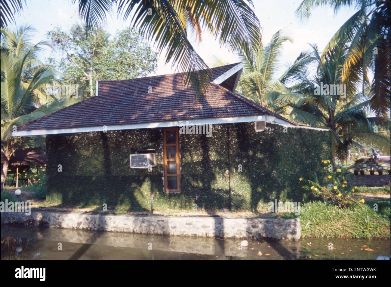 Kerala Case:- la forma visiva più distintiva dell'architettura Kerala è il lungo, ripido tetto inclinato costruito per proteggere le pareti della casa e per resistere al monsone pesante, normalmente posato con piastrelle o labirinto di paglia di foglie di palma, sostenuto su un telaio del tetto in legno duro e legno. Il Kerala è uno stato che riceve le precipitazioni per almeno 6 mesi in un anno e per un tale clima, i tetti inclinati sono sempre i migliori. L'architettura del Kerala segue Thatchu Shasthra, una scienza della Falegnameria che regola le sfumature dell'edificio/costruzione. Foto Stock