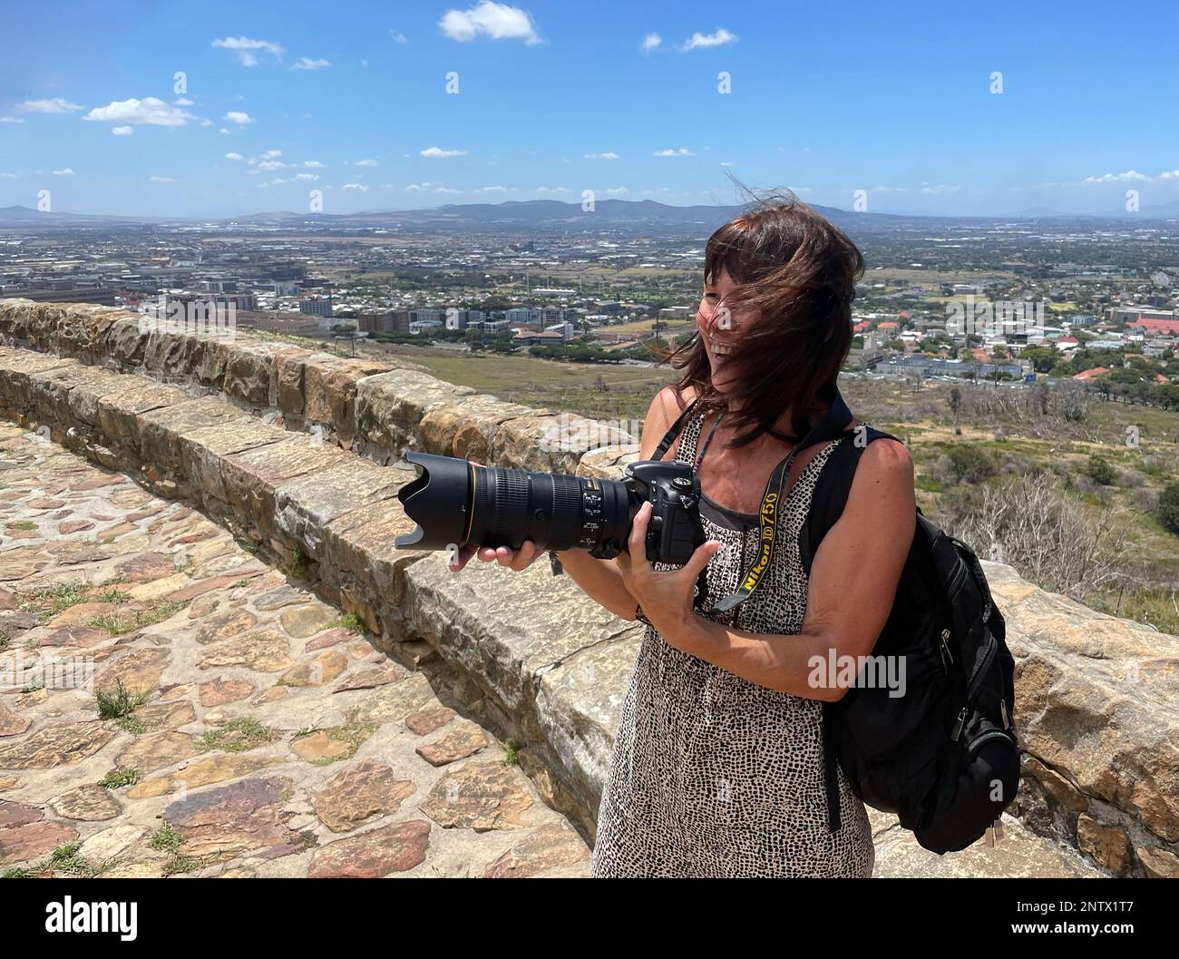 Città del Capo, Sudafrica. 2023. Turista tenendo macchina fotografica con i capelli che soffiano nei suoi occhi ad un luogo popolare di turismo. Foto Stock