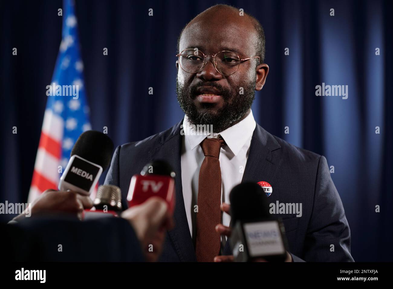 Giovane uomo fiducioso deputato o presidente in tuta elegante che parla ai microfoni dei giornalisti durante la conferenza stampa durante l'evento politico Foto Stock