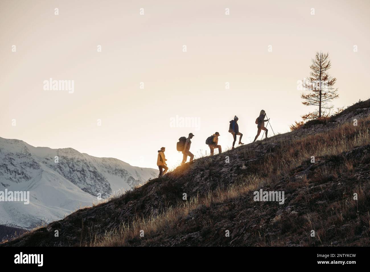 Gruppo di turisti silhouettes passeggiate con zaini in montagna Foto Stock